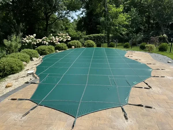 Green LOOP-LOC mesh safety cover fitted over a landscaped pool